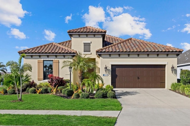 mediterranean / spanish house featuring a front yard, driveway, an attached garage, and stucco siding