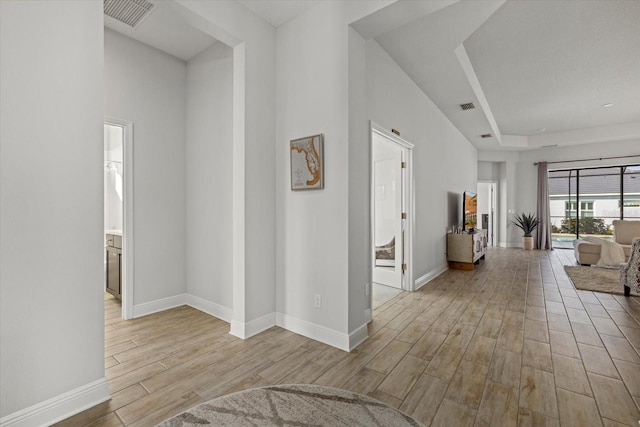 hall featuring visible vents, baseboards, and wood finished floors