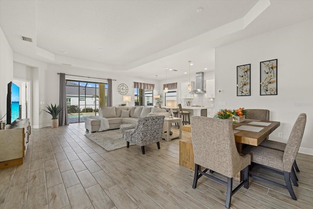 dining area featuring baseboards, a raised ceiling, visible vents, and wood tiled floor