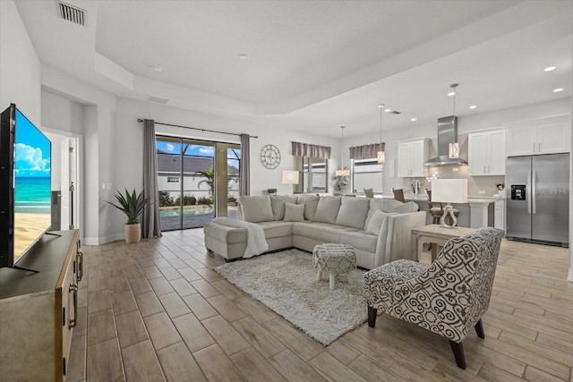 living room featuring a tray ceiling, recessed lighting, visible vents, wood tiled floor, and baseboards