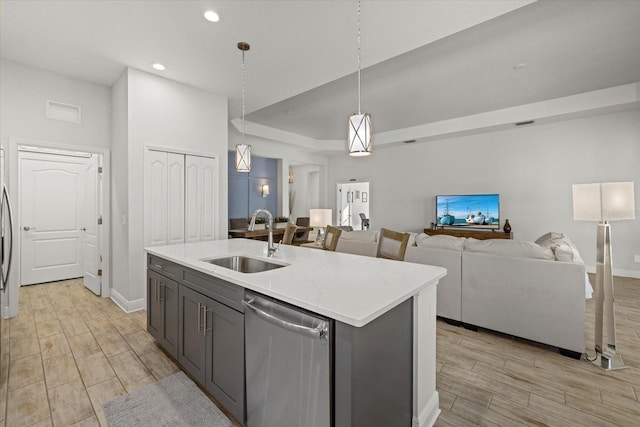 kitchen featuring light wood finished floors, visible vents, a raised ceiling, stainless steel dishwasher, and a sink