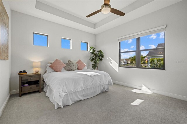 bedroom featuring ceiling fan, a tray ceiling, carpet flooring, and baseboards