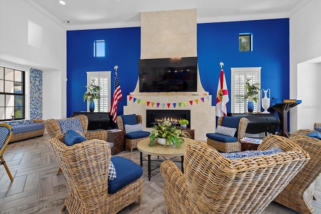 living area featuring a large fireplace, ornamental molding, and a healthy amount of sunlight