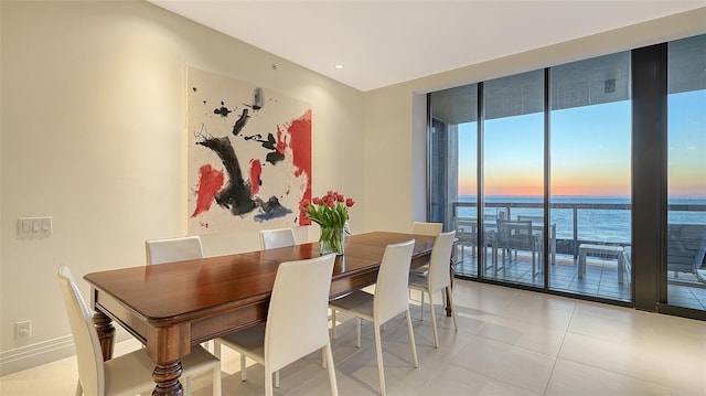 dining room with a water view, light tile patterned floors, and baseboards