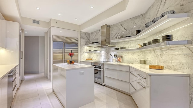 kitchen featuring wall chimney exhaust hood, modern cabinets, visible vents, and oven