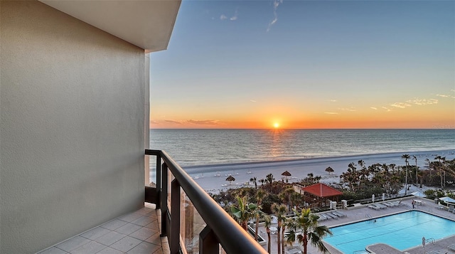 balcony at dusk featuring a water view