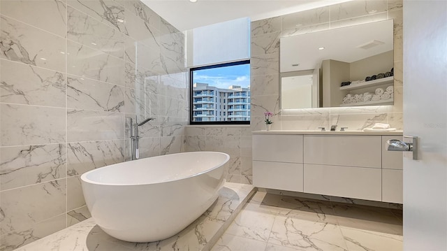 full bath with visible vents, a soaking tub, marble finish floor, vanity, and stone wall