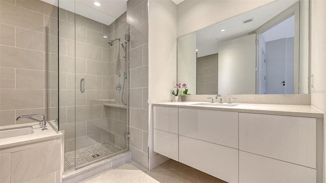 bathroom with tile walls, visible vents, a shower stall, vanity, and tile patterned flooring