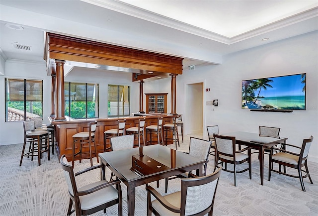 dining space featuring decorative columns, light colored carpet, visible vents, ornamental molding, and a community bar