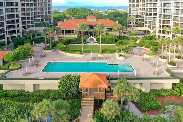 pool featuring a water view, a hot tub, and a patio