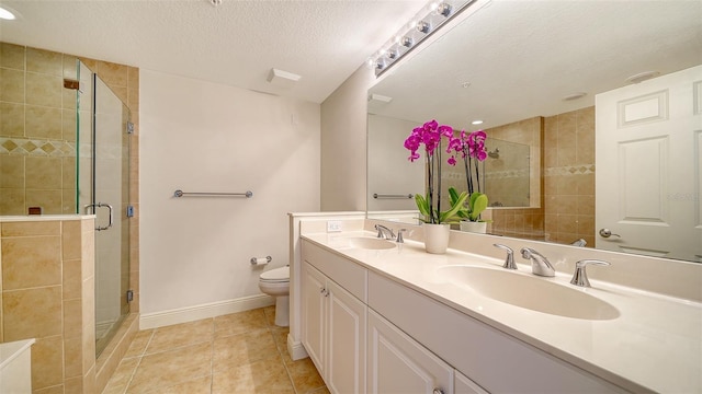 bathroom with toilet, a stall shower, tile patterned floors, a textured ceiling, and a sink