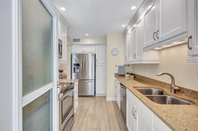 kitchen with visible vents, white cabinets, appliances with stainless steel finishes, wood finish floors, and a sink