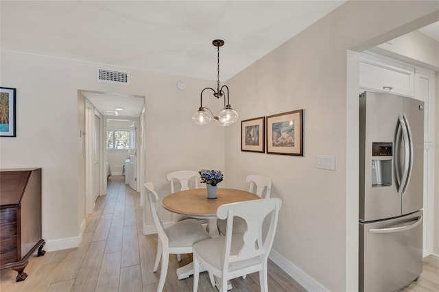 dining area featuring light wood finished floors, visible vents, and baseboards