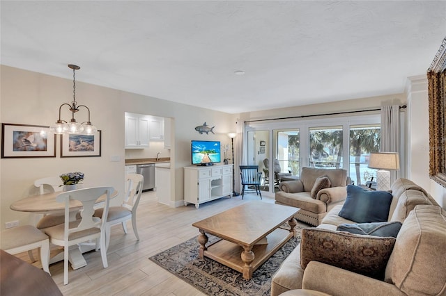 living room with light wood-style flooring, baseboards, and a notable chandelier