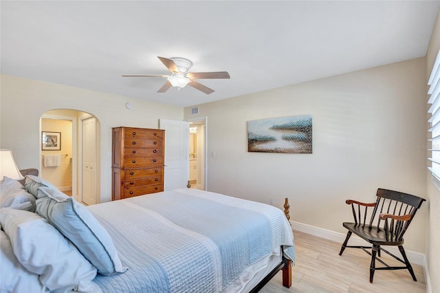 bedroom featuring visible vents, arched walkways, baseboards, light wood-style flooring, and ceiling fan