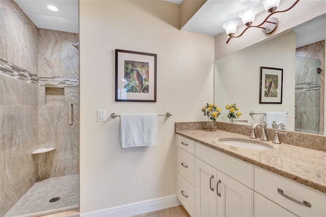 bathroom featuring a shower stall, baseboards, a chandelier, and vanity