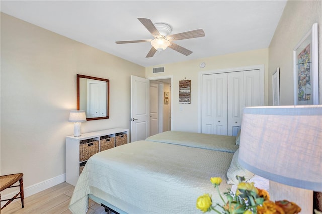 bedroom with a ceiling fan, visible vents, baseboards, a closet, and light wood finished floors