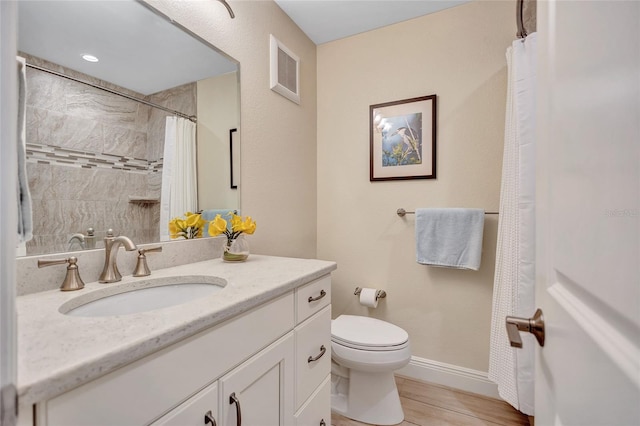 full bath featuring toilet, wood finished floors, vanity, visible vents, and baseboards