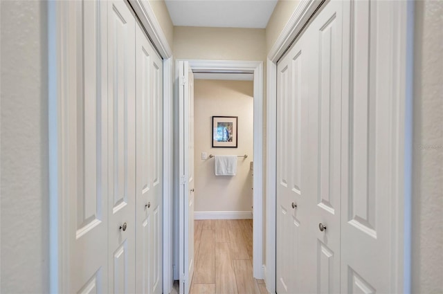 hall featuring light wood-type flooring and baseboards