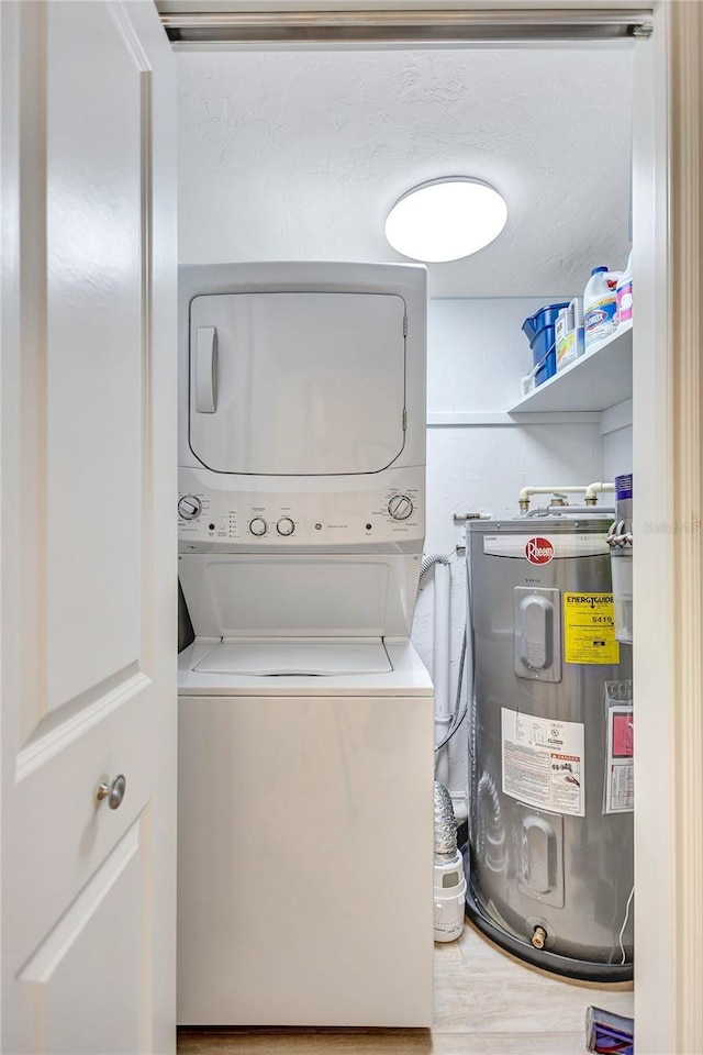 laundry room featuring stacked washer / drying machine, laundry area, water heater, and wood finished floors