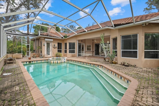 outdoor pool with a lanai, a patio area, ceiling fan, and an in ground hot tub