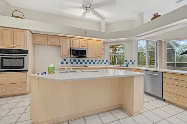 kitchen featuring tasteful backsplash, light brown cabinets, stainless steel appliances, and light countertops