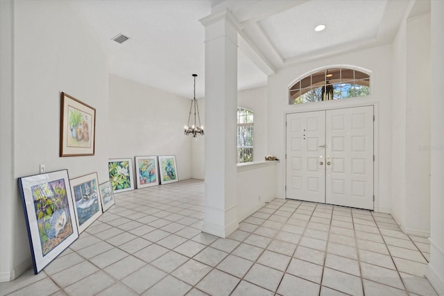 entrance foyer with visible vents, a notable chandelier, baseboards, and light tile patterned floors