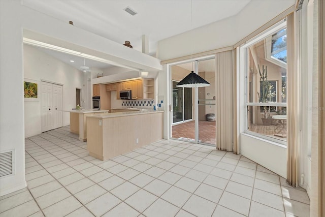 kitchen featuring light tile patterned floors, light countertops, appliances with stainless steel finishes, and light brown cabinetry