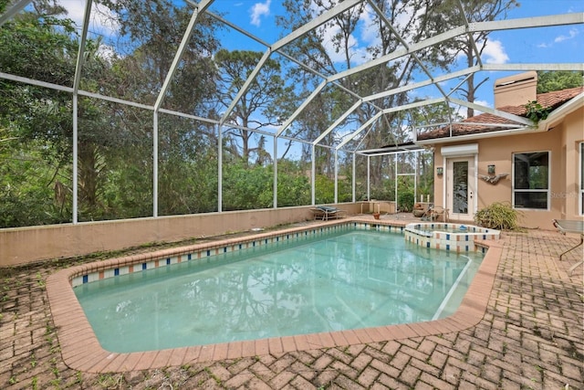 view of swimming pool featuring a pool with connected hot tub, a patio, and a lanai