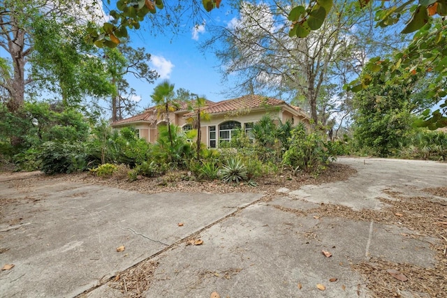 view of side of home featuring a tiled roof and stucco siding