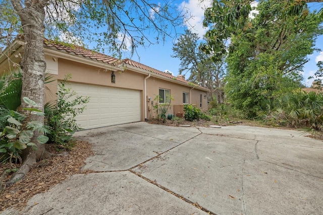 view of front of home featuring a garage, driveway, a tile roof, and stucco siding