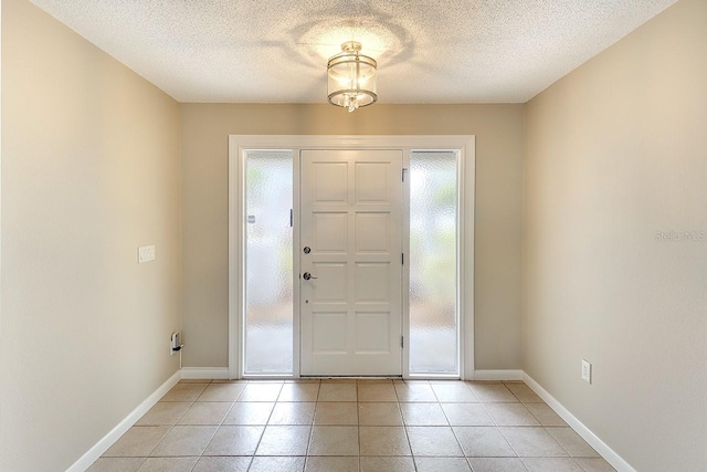 foyer with light tile patterned floors, baseboards, and a textured ceiling