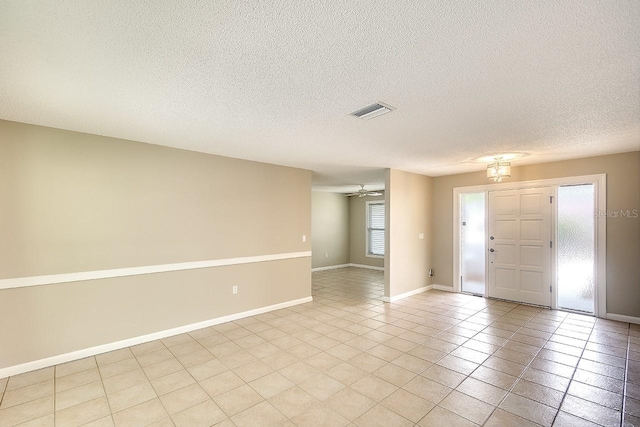 entryway featuring light tile patterned floors, visible vents, ceiling fan, a textured ceiling, and baseboards