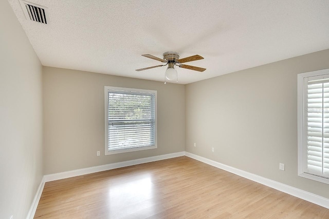 spare room featuring light wood-type flooring, visible vents, ceiling fan, and baseboards