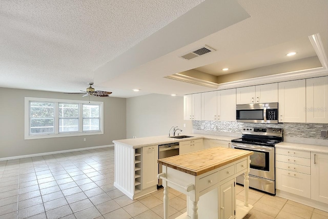 kitchen with appliances with stainless steel finishes, wood counters, visible vents, and tasteful backsplash