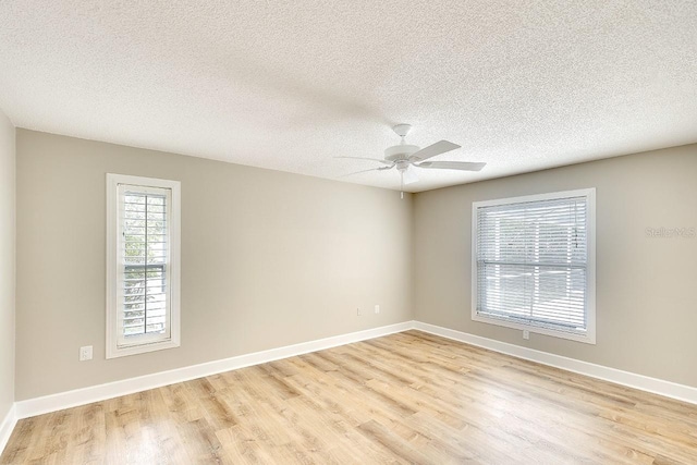 spare room featuring light wood-type flooring, a textured ceiling, baseboards, and a ceiling fan