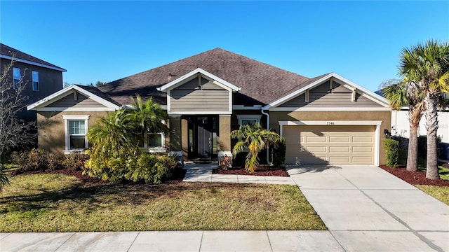 view of front of property featuring a garage, roof with shingles, driveway, and a front lawn