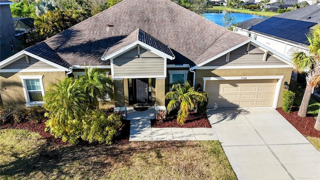 view of front of house featuring a shingled roof, concrete driveway, a water view, and a garage