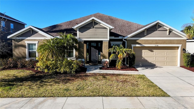 view of front of home with driveway, an attached garage, a shingled roof, and a front yard