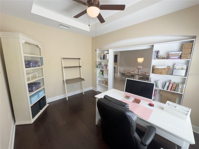 office area with wood finished floors, a ceiling fan, visible vents, baseboards, and a raised ceiling