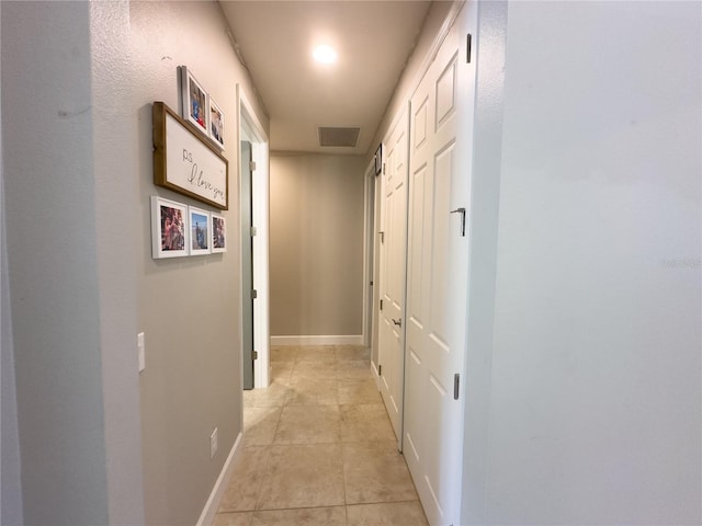 hall with light tile patterned floors, baseboards, and visible vents