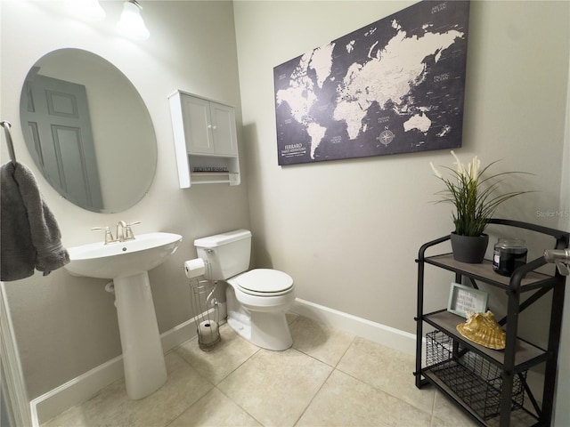 half bath featuring baseboards, toilet, and tile patterned floors