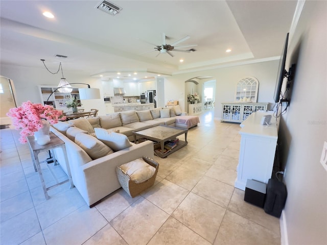 living area featuring arched walkways, recessed lighting, visible vents, a ceiling fan, and a tray ceiling