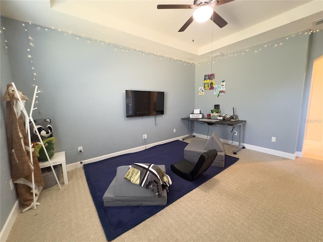 workout area with ceiling fan, a tray ceiling, carpet, and baseboards