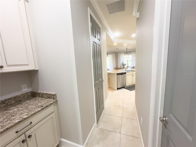 corridor with light tile patterned flooring, a sink, visible vents, baseboards, and ornamental molding