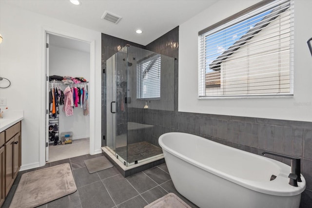 full bathroom with a freestanding tub, vanity, visible vents, and a shower stall