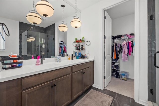 full bath featuring double vanity, a sink, a shower stall, and a spacious closet