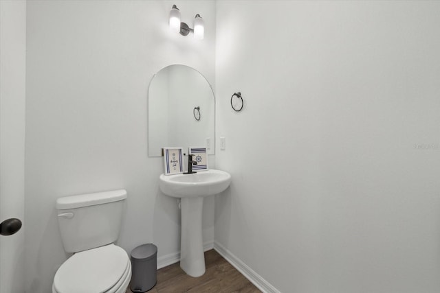 bathroom with wood finished floors, toilet, and baseboards