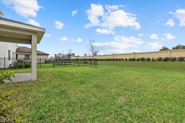 view of yard with a trampoline and fence