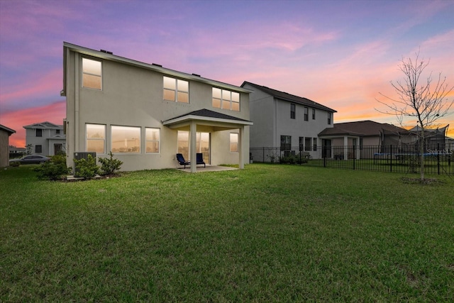 rear view of property featuring a patio area, fence, a lawn, and stucco siding